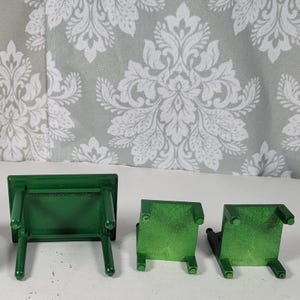 Puede incluir: Tres peque&ntilde;as mesas de madera verde. Las mesas son rectangulares con cuatro patas cada una. Las mesas est&aacute;n dispuestas en fila, con una mesa en posici&oacute;n vertical y las otras dos al rev&eacute;s. El fondo es un estampado floral gris y blanco.