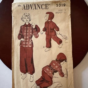 May include: Vintage Advance pattern envelope featuring illustrations of children's clothing. The envelope displays a plaid outfit and a hooded suit. The text reads "ADVANCE" and "5319". The size is 2, breast 21.