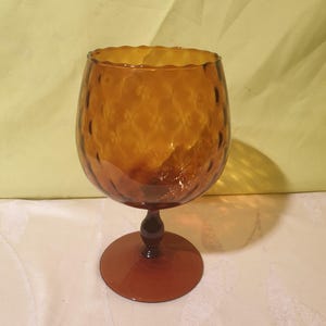 May include: A brown glass goblet with a textured surface and a wide base.