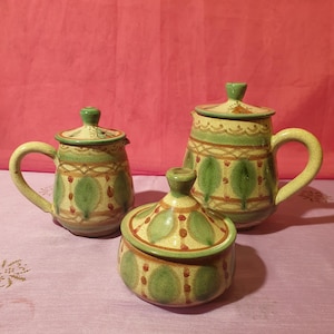 Peut inclure: Un ensemble de trois théières en céramique avec des motifs verts, bruns et rouges. Les théières ont un style traditionnel et sont parfaites pour servir le thé.
