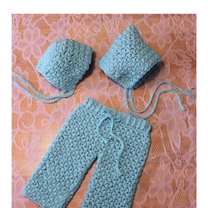 May include: A set of crocheted baby clothes in a light blue color. The set includes a hat and pants.