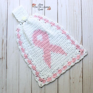 May include: White crochet dish towel with a pink ribbon design. The towel has a loop for hanging and a button.
