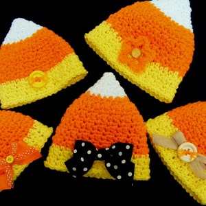 May include: Five crocheted candy corn hats in orange, yellow, and white. Each hat has a different embellishment, including a bow, a flower, and buttons.