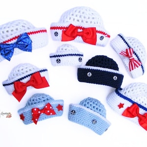 Könnte beinhalten: Eine Sammlung von neun gehäkelten Matrosenmützen in verschiedenen Farben, darunter Weiß, Blau und Rot. Die Mützen haben verschiedene Verzierungen, wie Schleifen, Knöpfe und Sterne.