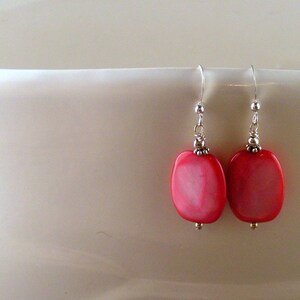 May include: A pair of silver dangle earrings with pink oval-shaped shell beads.