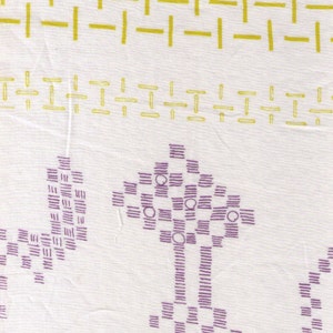 May include: White fabric with a repeating pattern of yellow and purple geometric shapes. The design includes horizontal lines, rectangles, and tree-like figures, creating a textured appearance. The fabric appears to be lightweight.