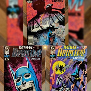 May include: Three vintage DC Detective Comics issues featuring Batman. The top cover shows a plane crash scene with a silhouette. The bottom left cover displays a blue Batman mask with a skull face. The bottom right cover depicts a bat and a skull.