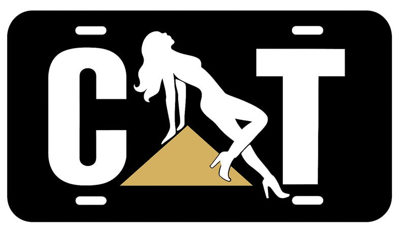 K&ouml;nnte beinhalten: Schwarzes Nummernschild mit dem Wort "CAT" in Wei&szlig;, das eine Silhouette einer Frau zeigt, die sich auf ein goldenes Dreieck st&uuml;tzt. Das Schild hat wei&szlig;e Rechtecke oben und unten.
