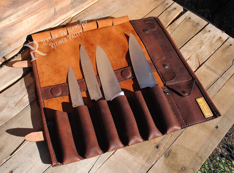 May include: A brown leather knife roll with four knives. The roll is made of a lighter brown leather with a darker brown leather trim and knife pockets. The knives have brown handles and silver blades. The text "LEATHER PATTERNS BY REFINED PALLET" is visible.