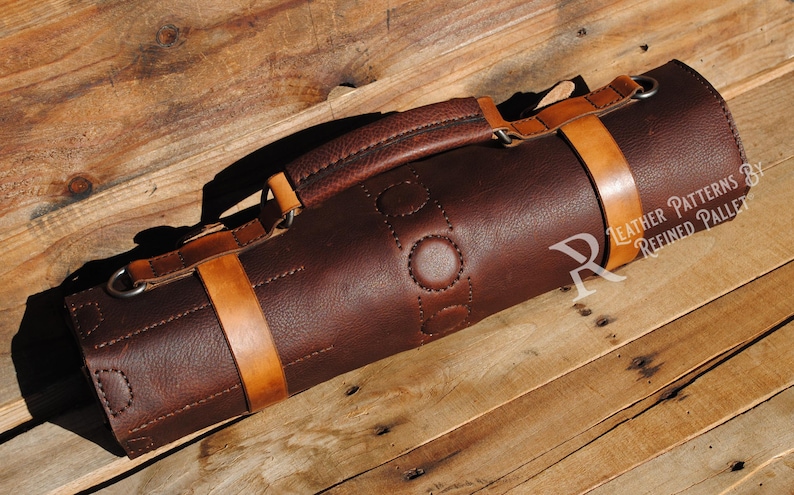 May include: A rolled-up, dark brown leather knife roll with tan leather straps and a handle. The roll is secured with two straps and features a stitched design. The text "Leather Patterns by Refined Pallet" is visible.
