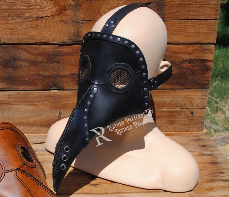 May include: A black leather plague doctor mask with a long beak and a mesh eye covering. The mask is worn on a mannequin head and has metal rivets and straps.
