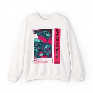 Puede incluir: Sudadera blanca de cuello redondo con un diseño de guardabosques espacial. El gráfico incluye una escena espacial con un personaje barbudo y las palabras "SPACE RANGERS" y "GALACTIC" en rosa y blanco.
