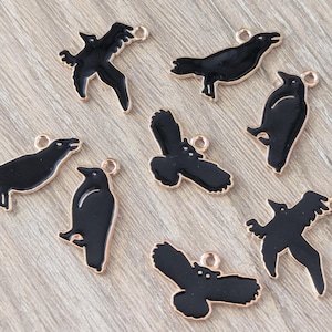 May include: Eight black crow charms with gold accents. The charms are in various poses and are perfect for jewelry making or crafting.