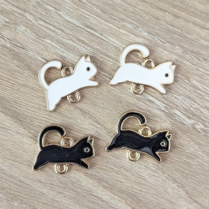 May include: Four metal cat charms with gold jump rings. Two charms are black and two charms are white.