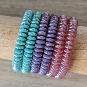 Puede incluir: Un juego de tres tazas de cerámica con un acabado mate moteado. Las tazas son de color crema, marrón claro y marrón oscuro. Cada taza tiene un asa redondeada y un diseño minimalista.