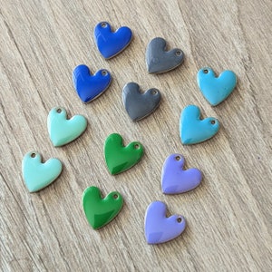 May include: Assortment of 12 heart-shaped charms in various colors, including blue, green, purple, and black. The charms are made of metal and have a shiny finish.