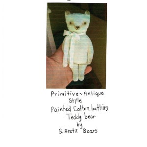 May include: A handmade, antique-style teddy bear made of painted cotton batting. The bear is light blue with a white scarf and the text "Gia" above it. The text "Primitive Antique Style" and "Teddy bear by S. Reetz Bears" are also present.