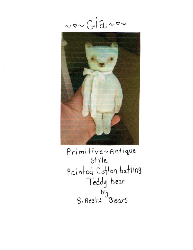 May include: A handmade, antique-style teddy bear made of painted cotton batting. The bear is light blue with a white scarf and the text "Gia" above it. The text "Primitive Antique Style" and "Teddy bear by S. Reetz Bears" are also present.