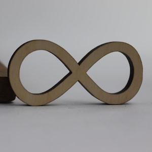 Peut inclure: Une découpe en bois en forme de symbole d'infini, de couleur brun clair et à la finition lisse.
