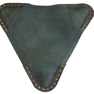 K&ouml;nnte beinhalten: Ein teal-farbener, dreieckiger Artikel aus Leder mit messingfarbenen Nieten an den Kanten. Das Leder hat ein abgenutztes Aussehen, und der Artikel ist mit dunklem Faden gen&auml;ht. Die Form erinnert an einen Sitz oder ein Kissen.