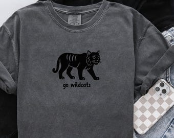May include: A charcoal gray long-sleeve shirt featuring a black tiger graphic and the words "go wildcats". The shirt is made of a soft material and has a crew neck.