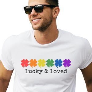 May include: White t-shirt with a rainbow of shamrocks and the text "lucky & loved" printed on the front.