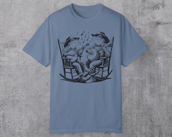 Könnte beinhalten: Ein hellblaues T-Shirt mit einem Motiv von zwei Fröschen, die Banjo spielen, während sie in Schaukelstühlen sitzen. Die Frösche tragen Hüte und halten Musikinstrumente.