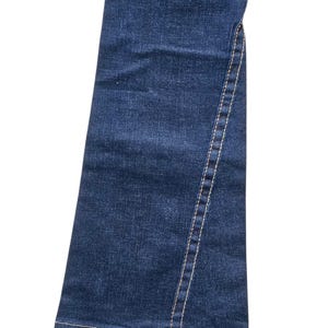 May include: Close-up of a pair of dark blue denim jeans. The jeans have a flared leg and a visible seam with white stitching running down the side. The denim has a classic, textured appearance.