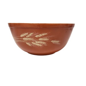 Puede incluir: Un tazón de mezcla de cerámica marrón con un diseño de trigo. El tazón es redondo y tiene un acabado liso y brillante.