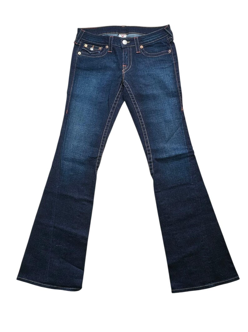 May include: Dark wash denim jeans with a flared leg. The jeans feature orange stitching, a button and zipper closure, and classic five-pocket styling. The back pockets have a signature design. The jeans are displayed on a white background.