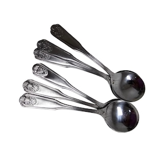 May include: Set of five silver spoons with ornate handles. The spoons are arranged in a fan shape, with the handles pointing towards the top of the image.