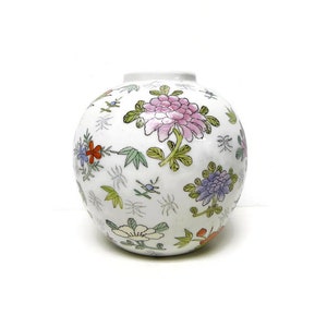 May include: A white ceramic vase with a round shape and a floral design. The vase is decorated with pink, purple, red, and green flowers.