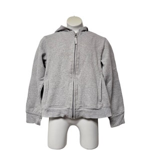May include: A heather gray zip-up hoodie with a hood and front pockets. The jacket is displayed on a white mannequin. The hoodie is made of a soft, comfortable material.