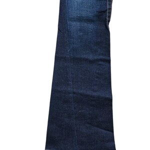 May include: Dark wash denim jeans with a flared leg. The jeans have white stitching along the seams and a classic five-pocket design. The fabric has a slight fade, giving it a worn look.