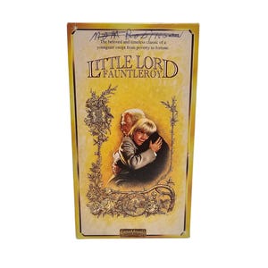 May include: A yellow VHS tape case with a picture of an older man and a young boy hugging. The title of the movie is "Little Lord Fauntleroy" and the text "The beloved and timeless classic of a youngster swept from poverty to fortune." is printed on the case.