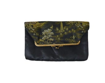 Puede incluir: Bolso de mano de satén negro con cierre dorado. La solapa presenta un diseño de paisaje detallado en negro, dorado y verde. El bolso es de forma rectangular, adecuado para eventos formales u ocasiones especiales.