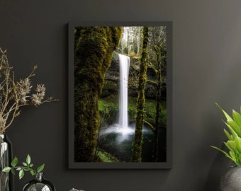 Peut inclure: Une photographie d'une cascade qui dévale une paroi rocheuse recouverte de mousse dans une forêt luxuriante et verte. L'eau est blanche et la forêt est d'un vert éclatant.