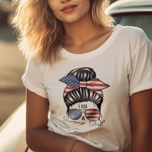 Könnte beinhalten: Weißes T-Shirt mit einer Grafik, die eine Frisur einer Frau mit einem amerikanischen Flaggen-Bandana und Sonnenbrille zeigt. Die Sonnenbrille hat ein amerikanisches Flaggen-Design und den Text "I AM A Grumpy Girl".
