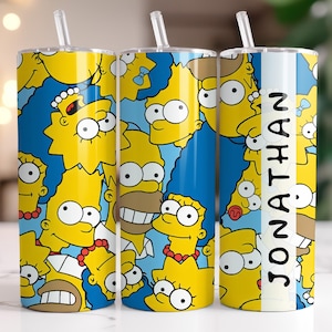 Op de afbeelding: Drie gele en blauwe roestvrijstalen bekers met een patroon van de Simpsons-personages. De beker rechts heeft de naam "JONATHAN" erop gedrukt.
