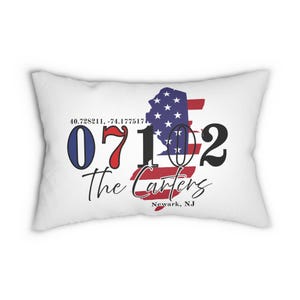 May include: White rectangular cushion featuring a design with the New Jersey state outline in red, white, and blue, with the text "The Carters" and the postcode 07102. The coordinates 40.728211, -74.177517 are also included.