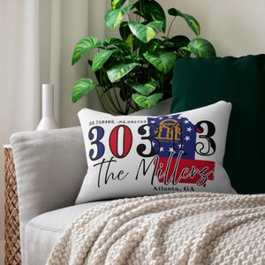 May include: White rectangular cushion with the text "303" in red and black, "The Millers" in black script, and "Atlanta, GA" in red. The cushion also features a Georgia state flag design.