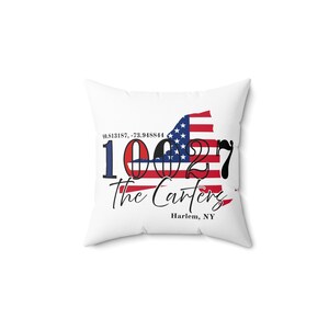 May include: White square cushion with a design featuring the New York state outline in the American flag colours. The design includes the text "10027 The Carters Harlem, NY" in black and red.