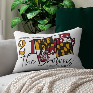 May include: White rectangular cushion featuring the text "21 The Browns" in black script, with the Maryland flag design. The cushion also has the coordinates 39.300018, -76.640835 and the text "Baltimore, MD".