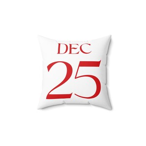 May include: A white square cushion featuring the red text "DEC 25". This decorative cushion is designed to add a festive touch to any room. A perfect item for Christmas decorations.