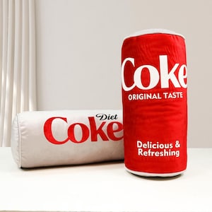 a can of coke next to a pillow on a table