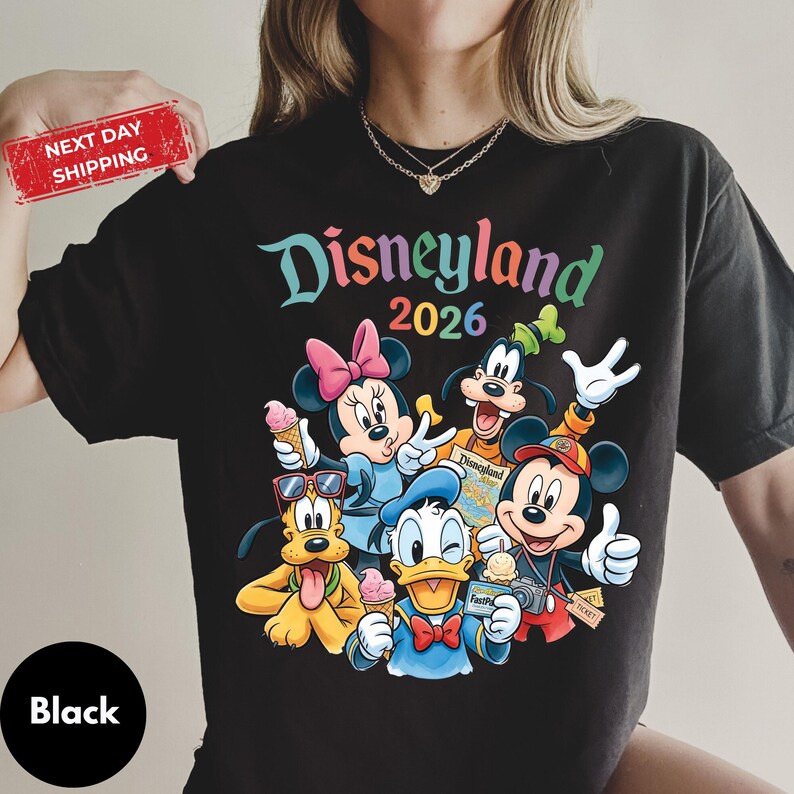 A person wearing a black t-shirt with a colorful graphic of Disney characters and text.