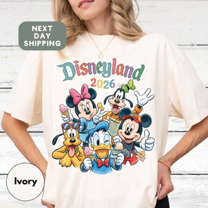 A woman wearing a white t-shirt with a colorful graphic of Disney characters from the theme park.