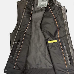 May include: Black leather motorcycle vest with a zipper closure and snap buttons. The vest has an orange lining and a yellow pocket on the inside. The label on the inside reads "Pro Rider Leathers U.S.A."