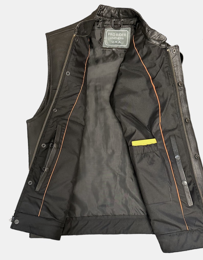 May include: Black leather motorcycle vest with a zipper closure and snap buttons. The vest has an orange lining and a yellow pocket on the inside. The label on the inside reads "Pro Rider Leathers U.S.A."