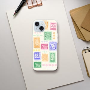 Puede incluir: Una funda de teléfono blanca con un collage de diseños de sellos postales coloridos. Los sellos muestran diversas ilustraciones y textos en tonos naranja, verde, rosa y azul. La funda está sobre una superficie blanca, con un bolígrafo y papel.